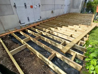 Structure de terrasse bois sur plots en cours de montage dans un jardin
