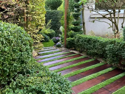 Allée de jardin avec marches en bois et haies bien entretenues