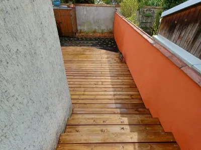 Terrasse en bois étroite longeant un mur avec finition soignée