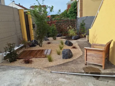 Jardin en rénovation avec allée de gravier, banc et plantations autour d’un petit espace extérieur
