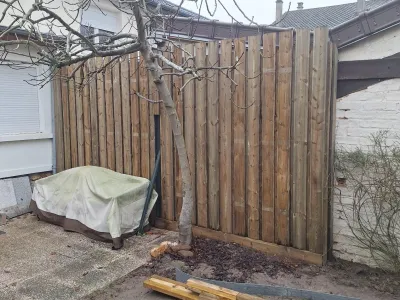 Espace extérieur avec palissade en bois et matériel couvert, début d’aménagement