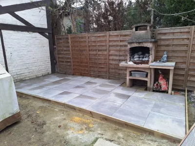 Cour avec barbecue et palissade en bois, début de décoration extérieure.