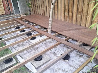 Terrasse en bois partiellement installée autour d’un arbre, zone d’aménagement.